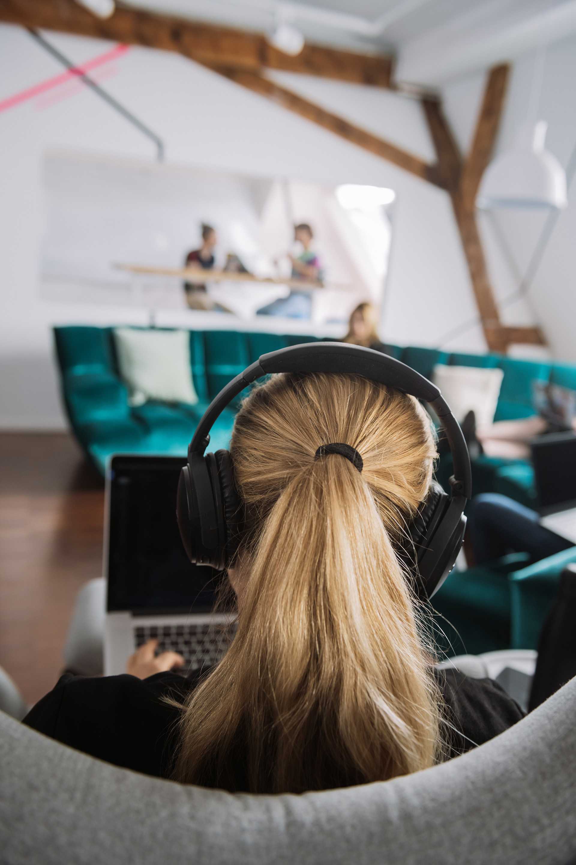 A woman on a computer, wearing headphones